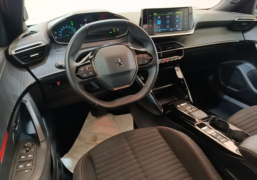 Intérieur de la Peugeot E-2008 électrique 2023 vu côté conducteur, volant cuir multifonctions et écran tactile central.