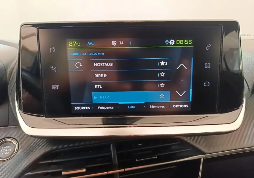 Écran tactile central allumé affichant la radio dans l’habitacle du Peugeot E-2008 électrique gris clair.