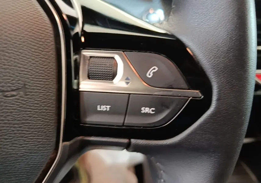 Gros plan sur les commandes gauche du volant cuir multifonctions du Peugeot E-2008 électrique gris clair 2023.