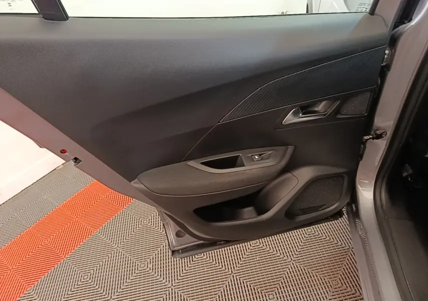 Vue intérieure de la porte arrière droite gris clair du Peugeot E-2008 électrique, avec panneau noir et commande de vitre.