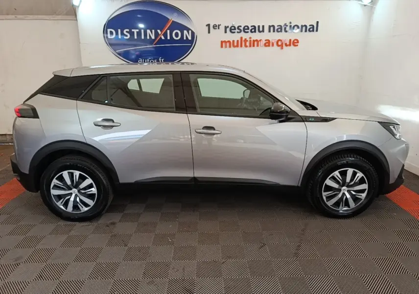 Peugeot E-2008 électrique gris clair en profil côté gauche, avec jantes alliage et toit noir contrasté.