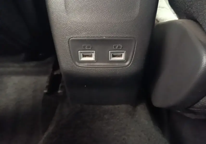 Prise double USB arrière sur console centrale noire dans l’habitacle du Peugeot E-2008 électrique gris clair.