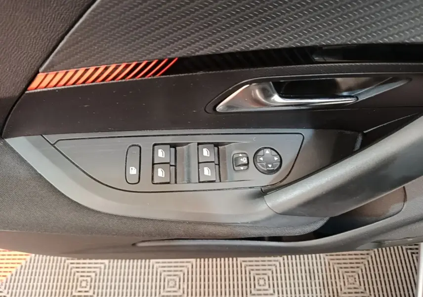 Gros plan sur la porte côté gauche du Peugeot E-2008 électrique gris clair, avec commandes des vitres et rétroviseurs.