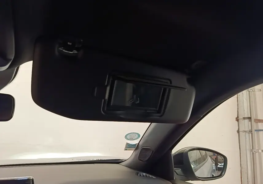 Vue intérieure côté passager du pare-soleil avec miroir, rétroviseur et partie du tableau de bord noir du Peugeot E-2008 gris clair.