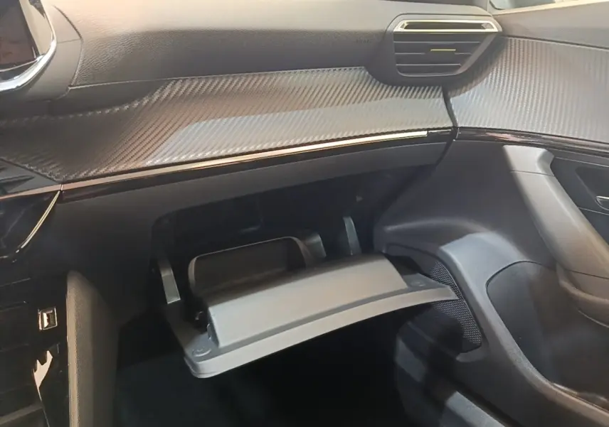 Vue intérieure côté passager du tableau de bord gris foncé et boîte à gants ouverte du Peugeot E-2008 électrique 2023.