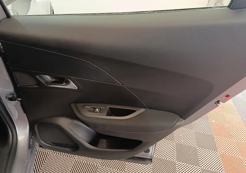 Vue intérieure de la porte côté gauche gris clair du Peugeot E-2008 électrique Active Pack 2023, avec commande de vitre.