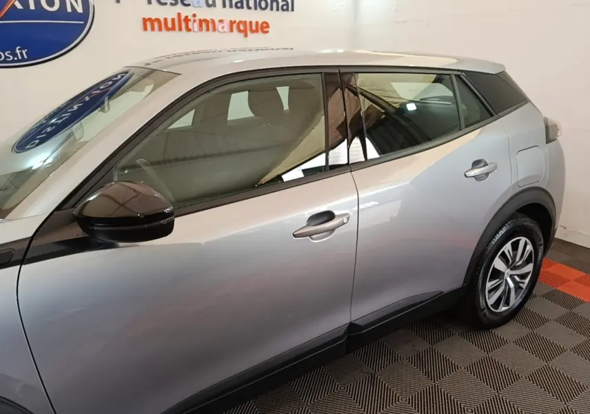 Vue de profil côté gauche du Peugeot E-2008 électrique gris clair, avec rétroviseur noir et jantes distinctives.