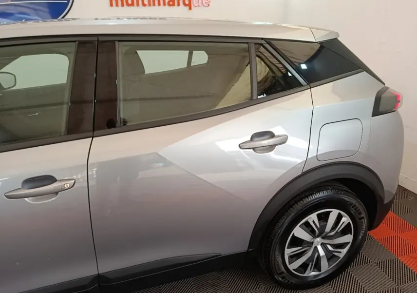Vue latérale droite d'un Peugeot E-2008 électrique gris clair, mettant en valeur la porte arrière et la roue arrière.