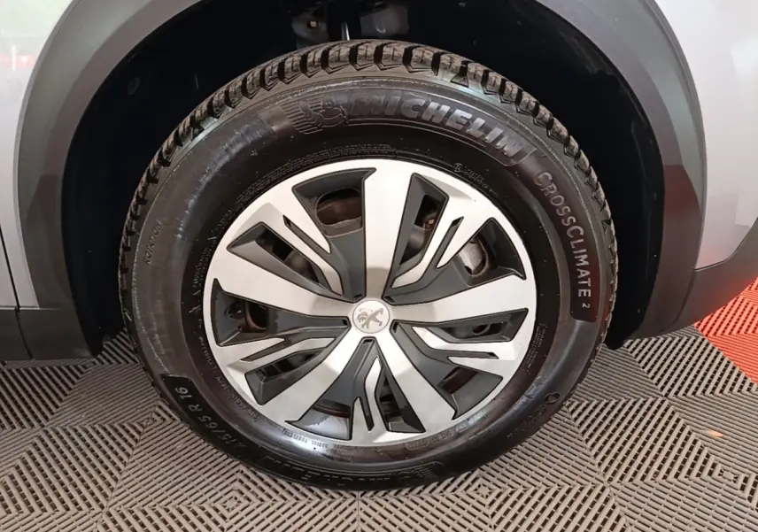 Gros plan sur la roue avant droite d’un Peugeot E-2008 électrique gris clair avec jante alliage et pneu Michelin CrossClimate 2.