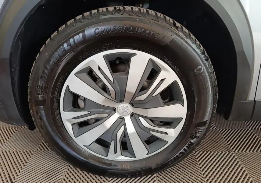 Gros plan sur la roue avant gauche gris clair du Peugeot E-2008 électrique avec jante stylisée et pneu Michelin CrossClimate 2.