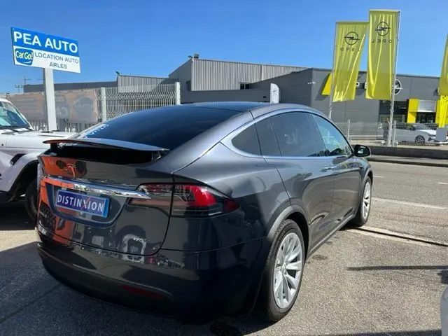 Vue 3/4 arrière droite d'une Tesla Model X gris métallisé 2019, avec vitres teintées et jantes argentées.