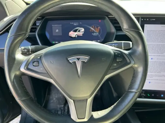 Vue rapprochée du volant de la Tesla Model X gris 2019, avec tableau de bord numérique et écran tactile visible.