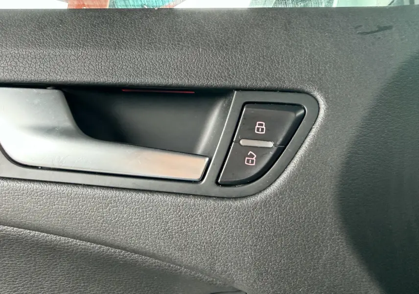 Poignée de porte intérieure côté gauche en plastique noir avec boutons de verrouillage d'une Audi A5 Sportback gris.