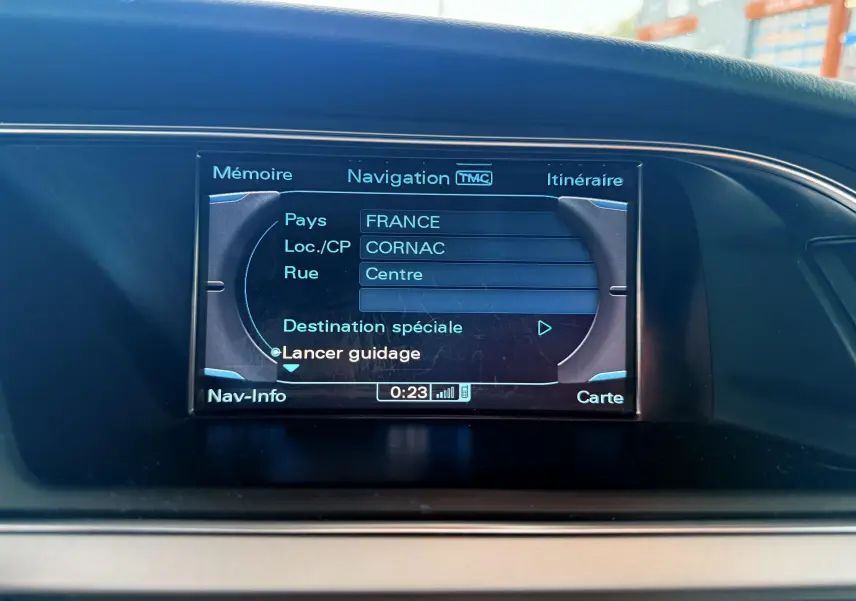 Écran de navigation central affichant un itinéraire en cours dans un Audi A5 gris, vue intérieure du tableau de bord.