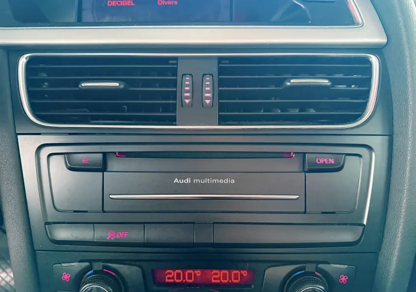 Vue rapprochée du tableau de bord de l'Audi A5 gris, mettant en valeur la console multimédia et la climatisation digitale.