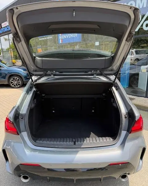 Vue arrière ouverte sur le coffre spacieux d'une BMW Série 1 118d Edition Sport gris foncé 2024, feux arrière LED visibles.