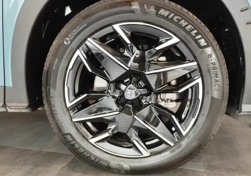 Gros plan sur la jante alliage noire diamantée 19'' du Peugeot 5008 Bleu Ingaro avec logo lion au centre.