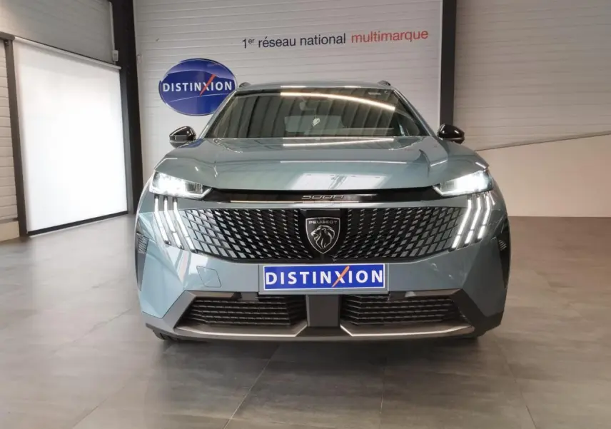 Vue de face du Peugeot 5008 2025 bleu Ingaro avec calandre noire et feux LED à griffes allumés.