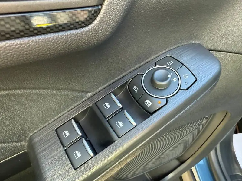 Gros plan sur les commandes de lève-vitres et rétroviseurs côté conducteur du Ford Kuga bleu 2024, finition ST-Line.
