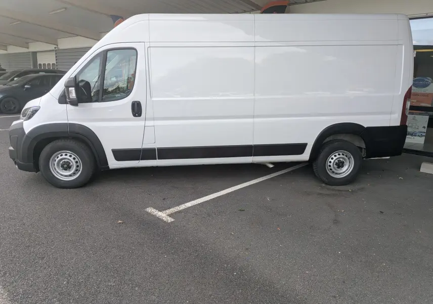 Fiat Ducato Fourgon blanc vu de profil côté gauche, stationné sous un abri avec détails noirs sur les bas de caisse.