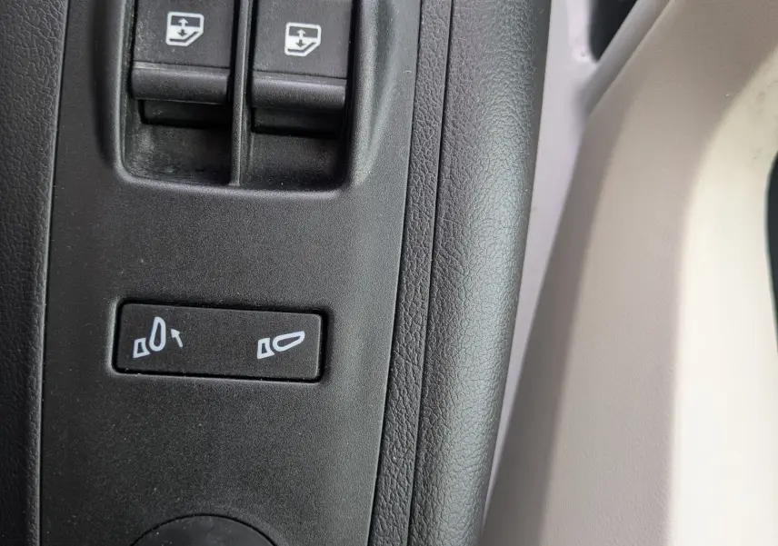 Gros plan sur les commandes de réglage des rétroviseurs et vitres côté conducteur du Fiat Ducato Fourgon blanc 2025.