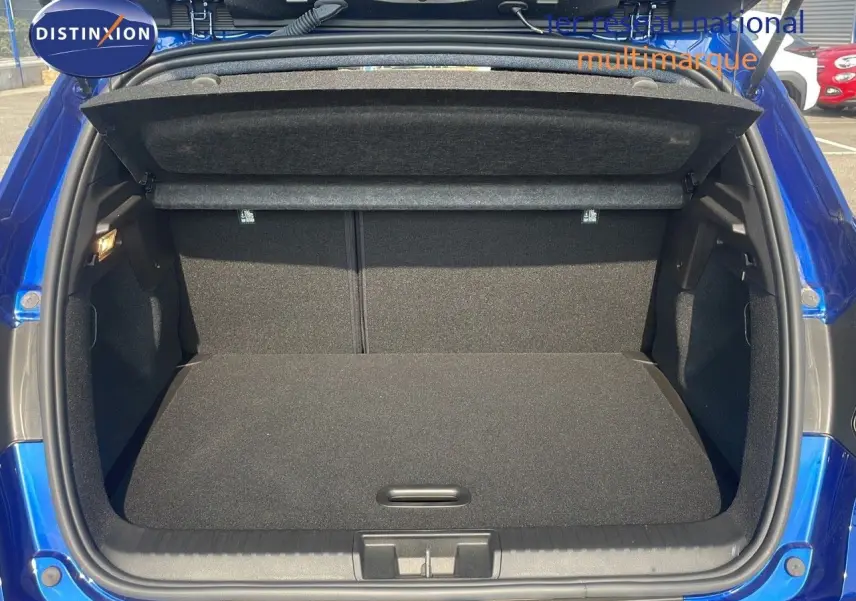 Coffre ouvert d'un Renault Captur bleu Iron Metal, vue arrière montrant l'espace de chargement vide et la plage arrière.