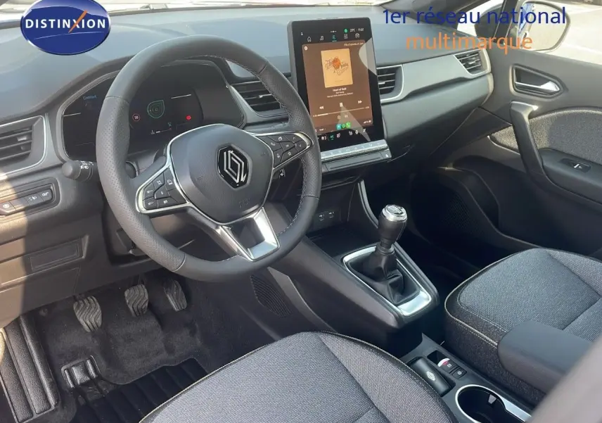Vue intérieure côté conducteur du Renault Captur 2025, tableau de bord moderne avec écran tactile vertical et levier de vitesse manuel.
