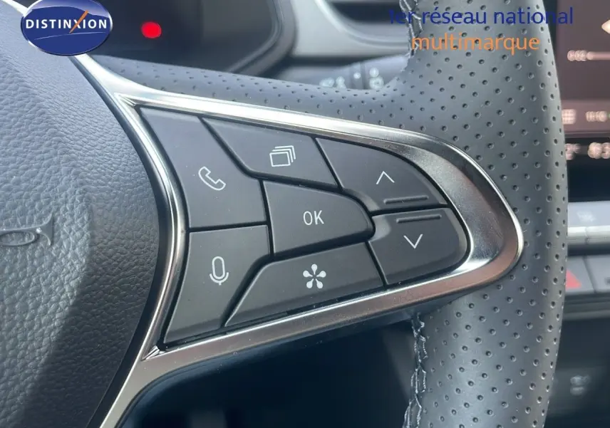 Gros plan sur les commandes multifonctions à droite du volant en cuir perforé du Renault Captur bleu Iron Metal 2025.