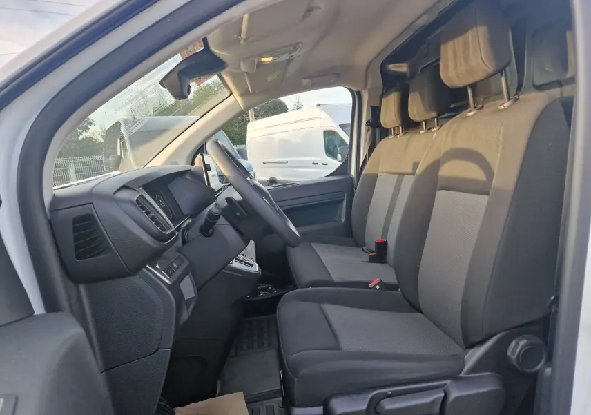 Intérieur du FIAT Scudo Fourgon blanc 2024, vue côté conducteur montrant les sièges avant et le tableau de bord.