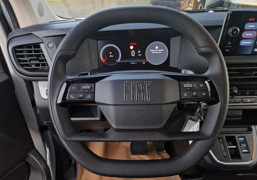 Vue rapprochée du volant noir du Fiat Scudo Fourgon 2024 avec tableau de bord digital et commandes intégrées.