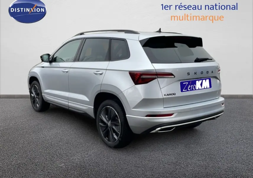 Vue 3/4 arrière droite d'un Skoda Karoq gris argent métallisé avec jantes noires et toit noir.