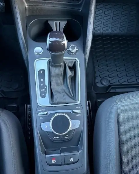 Vue rapprochée de la console centrale noire de l'Audi Q2 35 TFSI 150 S Tronic S Line avec levier de vitesse automatique et molette de contrôle.