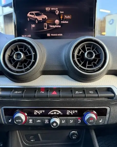 Vue rapprochée du tableau de bord de l'Audi Q2 noir 2023, avec écran tactile 8,3 pouces et commandes de climatisation digitales.