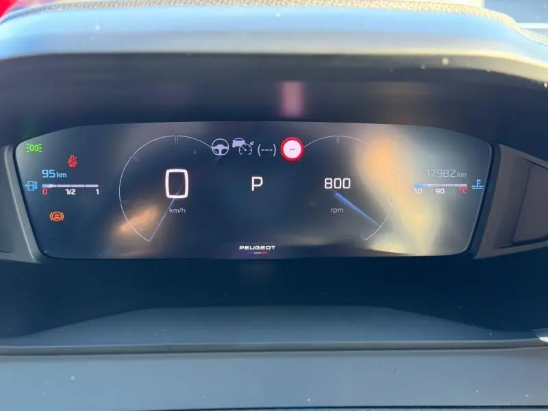 Vue frontale du tableau de bord numérique du Peugeot 2008 gris, affichant la vitesse, le régime moteur et les alertes.