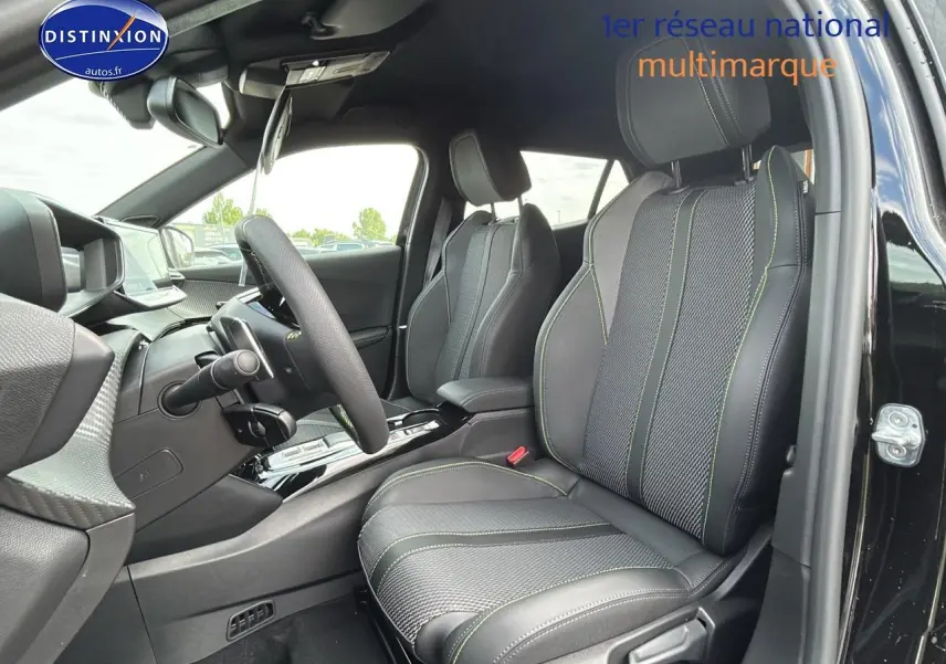 Vue intérieure côté conducteur du Peugeot 2008 noir 2025, sièges sport avec surpiqûres vertes et volant cuir multifonction.