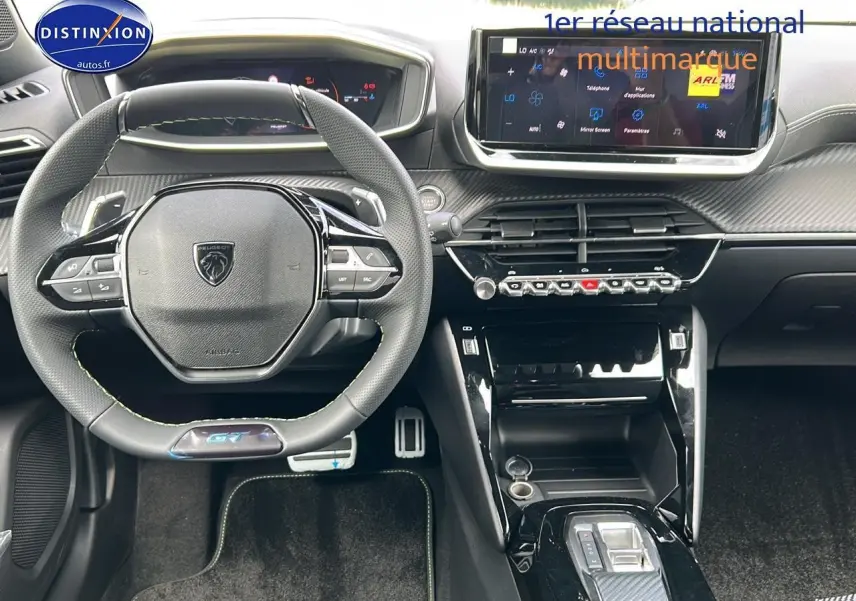 Vue intérieure frontale du tableau de bord et volant cuir noir avec logo Peugeot GT, écran tactile et console centrale moderne.