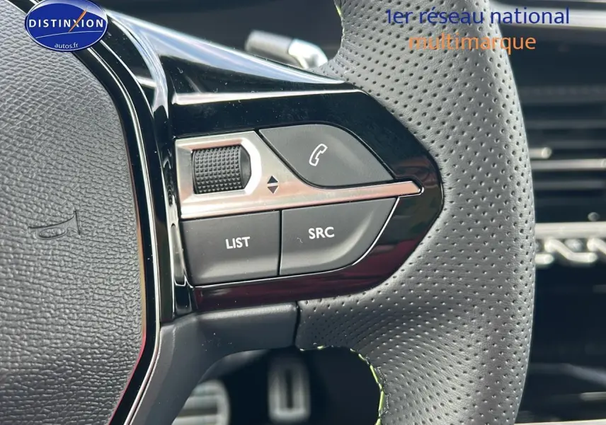 Gros plan sur les commandes gauche du volant cuir perforé du Peugeot 2008 noir hybride 2025.