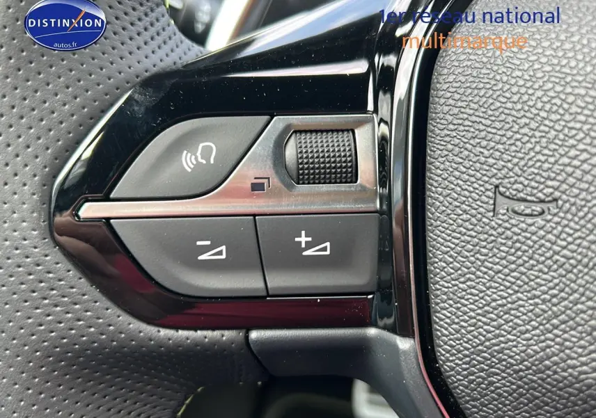 Gros plan sur les commandes gauche du volant cuir noir perforé du Peugeot 2008 1.2 hybrid 145 GT 2025.