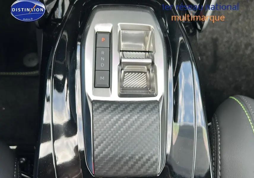 Vue rapprochée de la console centrale noire avec sélecteur de vitesses et finition carbone dans une Peugeot 2008 1.2 hybrid 145 GT.