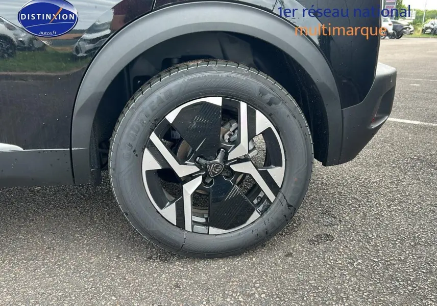 Gros plan sur la roue arrière droite noire d’un Peugeot 2008 1.2 hybrid 145 GT e-DCS6 avec jante alu bicolore.