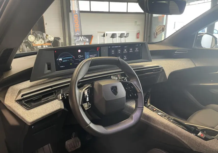 Vue intérieure du tableau de bord du Peugeot 5008 2025, volant compact cuir noir et double écran HD panoramique.