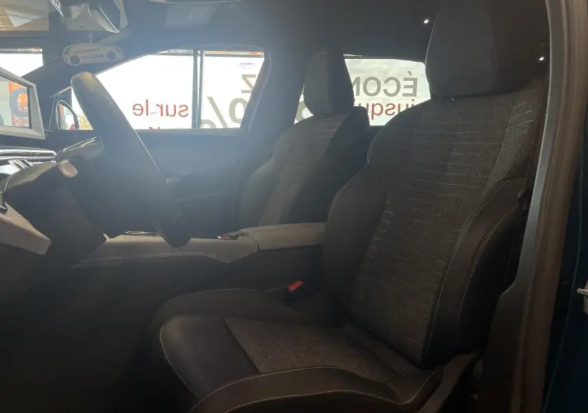 Vue intérieure côté conducteur du Peugeot 5008 bleu Obsession, sièges tissu gris et cuir noir avec surpiqûres contrastées.