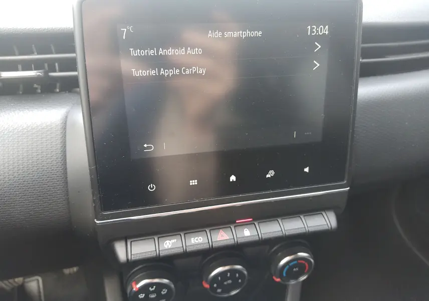 Écran tactile central avec tutoriels Android Auto et Apple CarPlay dans Renault Clio V gris, vue intérieure du tableau de bord.