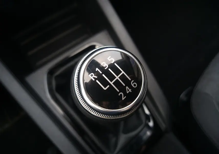 Gros plan sur le levier de vitesses manuel noir de la Renault Clio V 1.0 TCE 90ch, intérieur sombre.