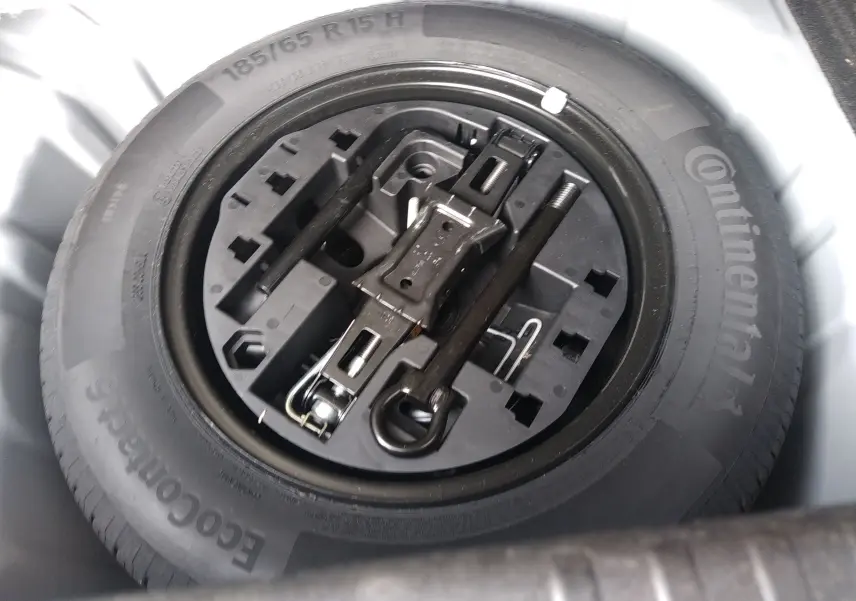 Roue de secours avec outillage intégré dans le coffre d'une Renault Clio V gris 2023, vue en plongée.