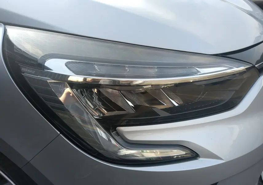 Gros plan sur le phare avant droit gris d'une Renault Clio V 2023, mettant en valeur ses lignes LED modernes.