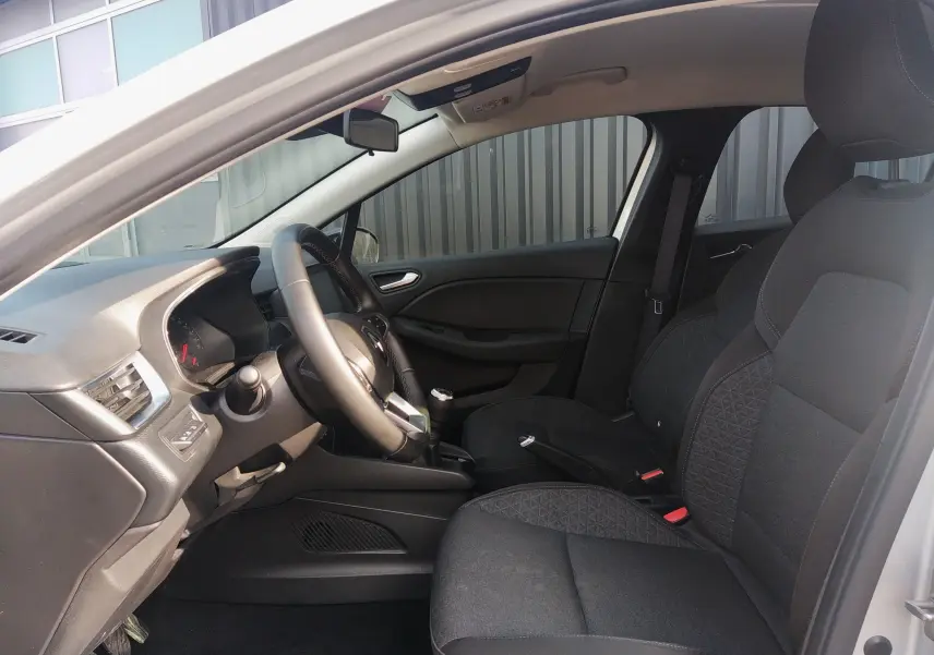 Vue intérieure côté conducteur de la Renault Clio V 2023, sièges tissu noir et volant multifonction.
