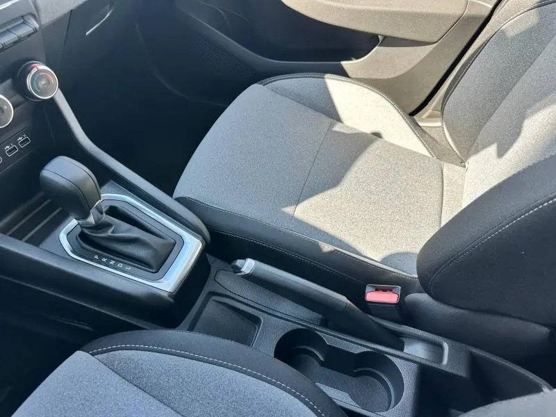 Gros plan intérieur sur la console centrale et siège avant gris clair de la Renault Clio 2025, avec levier de vitesse et frein à main.