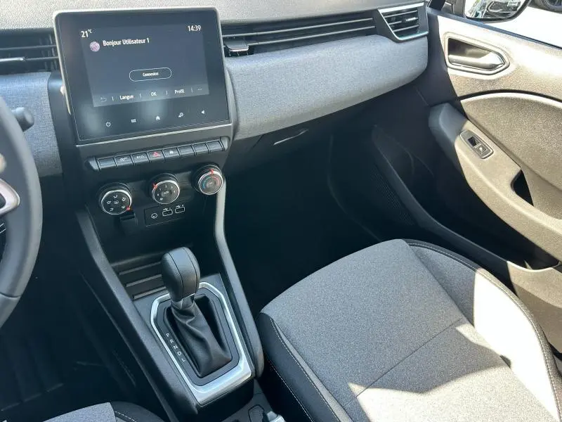 Vue intérieure côté passager de la Renault Clio 2025 gris Rafale, avec écran tactile et sellerie textile gris à motif 3D.