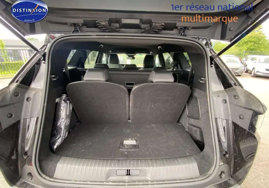 Coffre ouvert vu de l'arrière d'un Peugeot 5008 noir, montrant les sièges arrière partiellement relevés et l'habitacle.